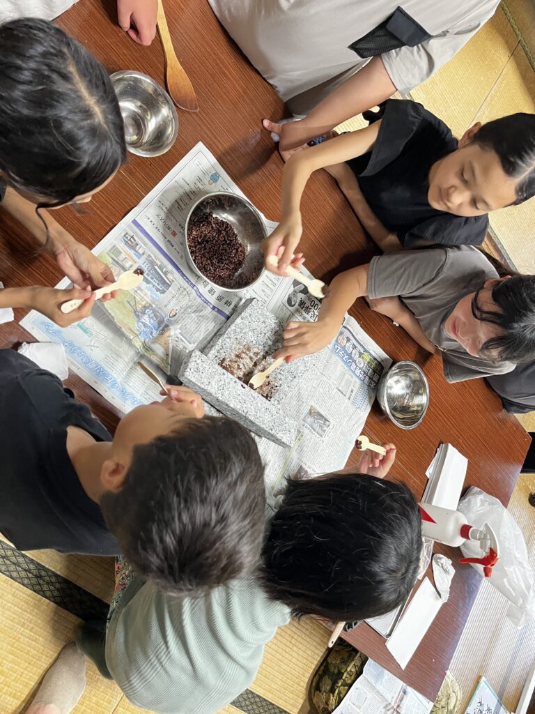 石臼で焙煎したカカオ豆を挽く子どもたちの様子