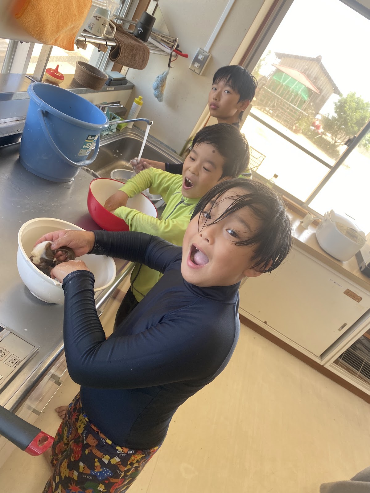 台所でタコの塩もみをする3人の子どもの様子