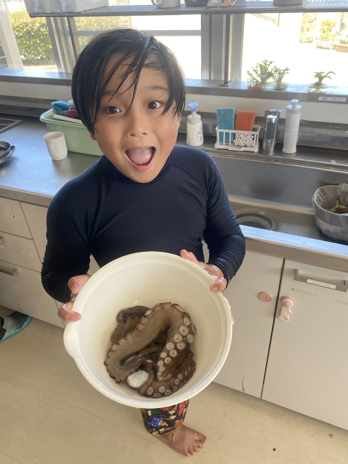 過去最大のタコが入ったバケツを掲げる子どもの様子