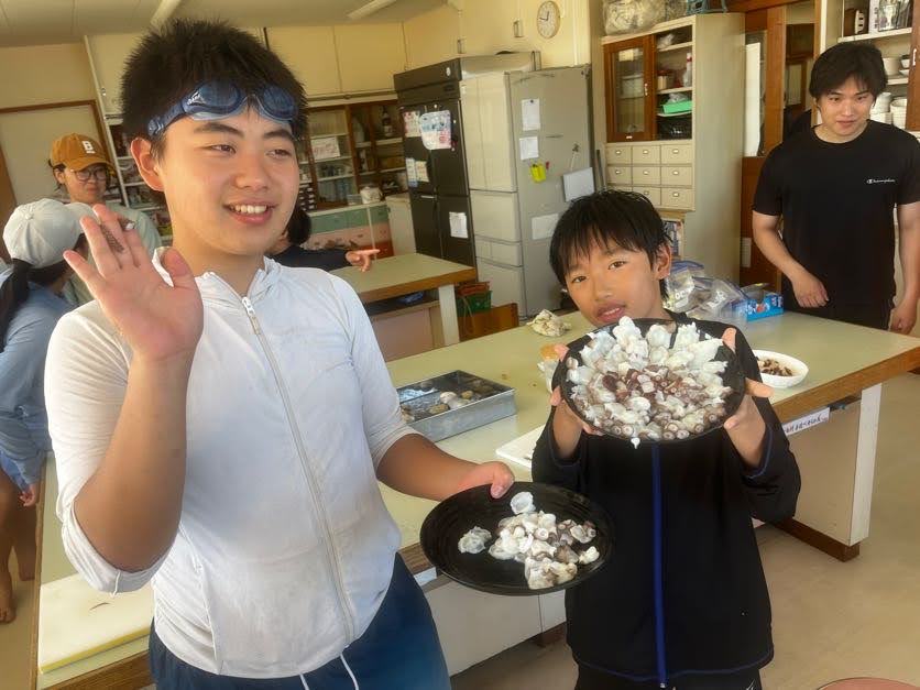 調理したタコの皿を掲げる子どもたちの様子
