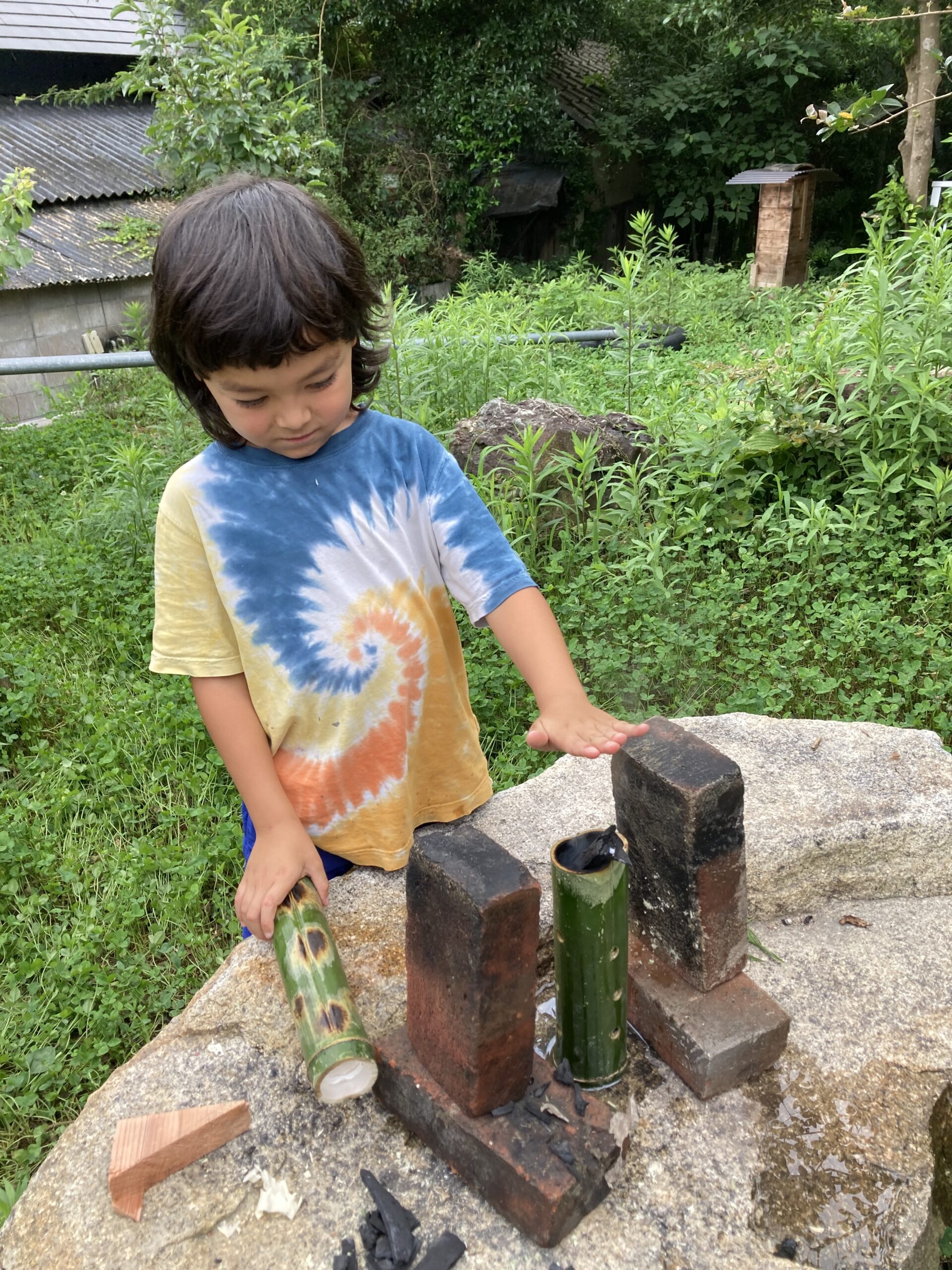 青竹を炙る道具を手にする子どもの様子