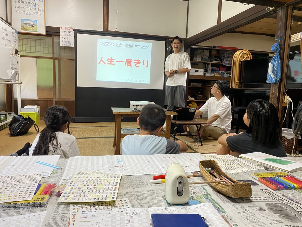 スクリーンに「人生一度きり」というメッセージを映し出し、話す講師の様子
