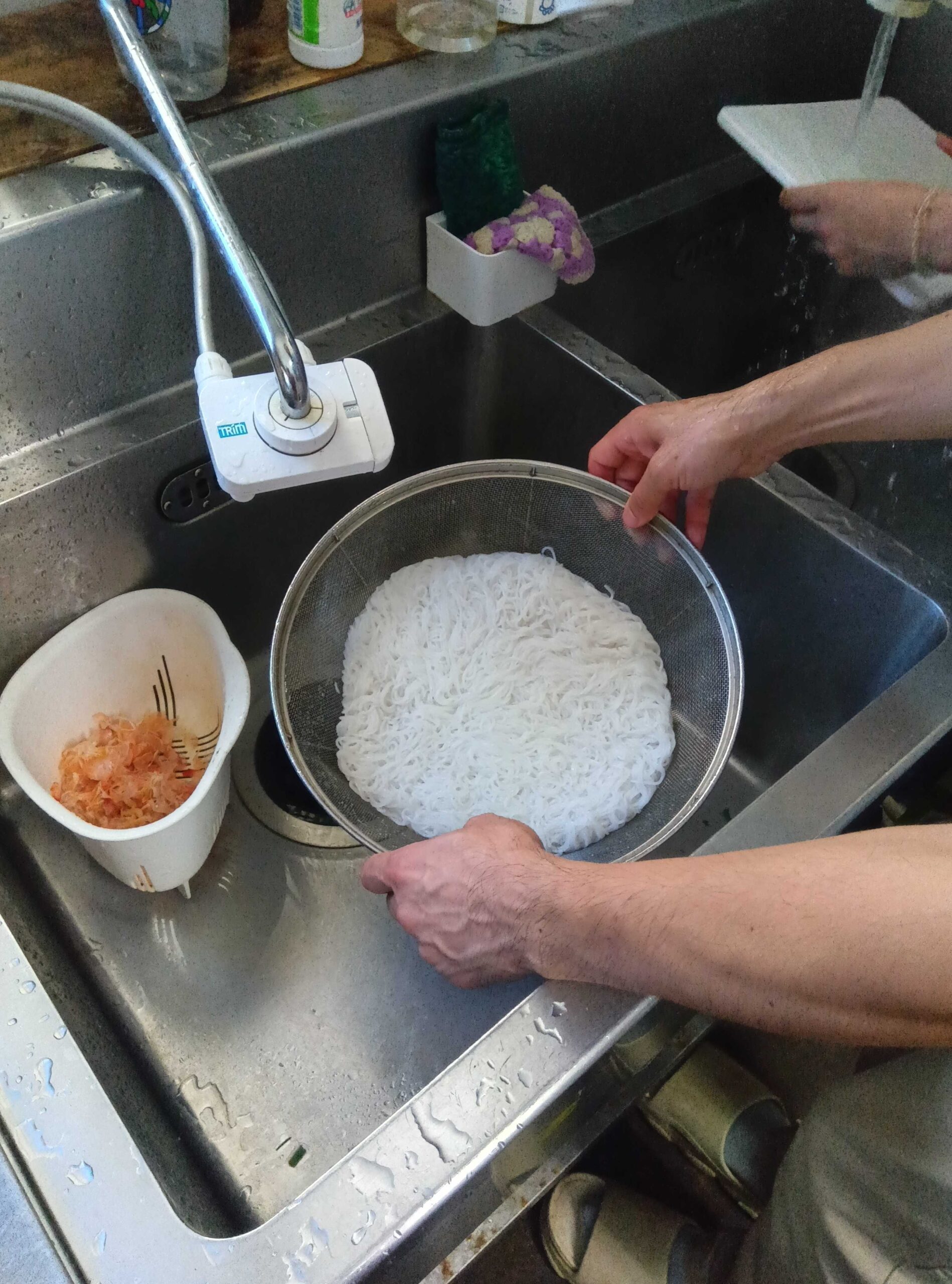 お米でできたフォーの麺をザルで洗う様子