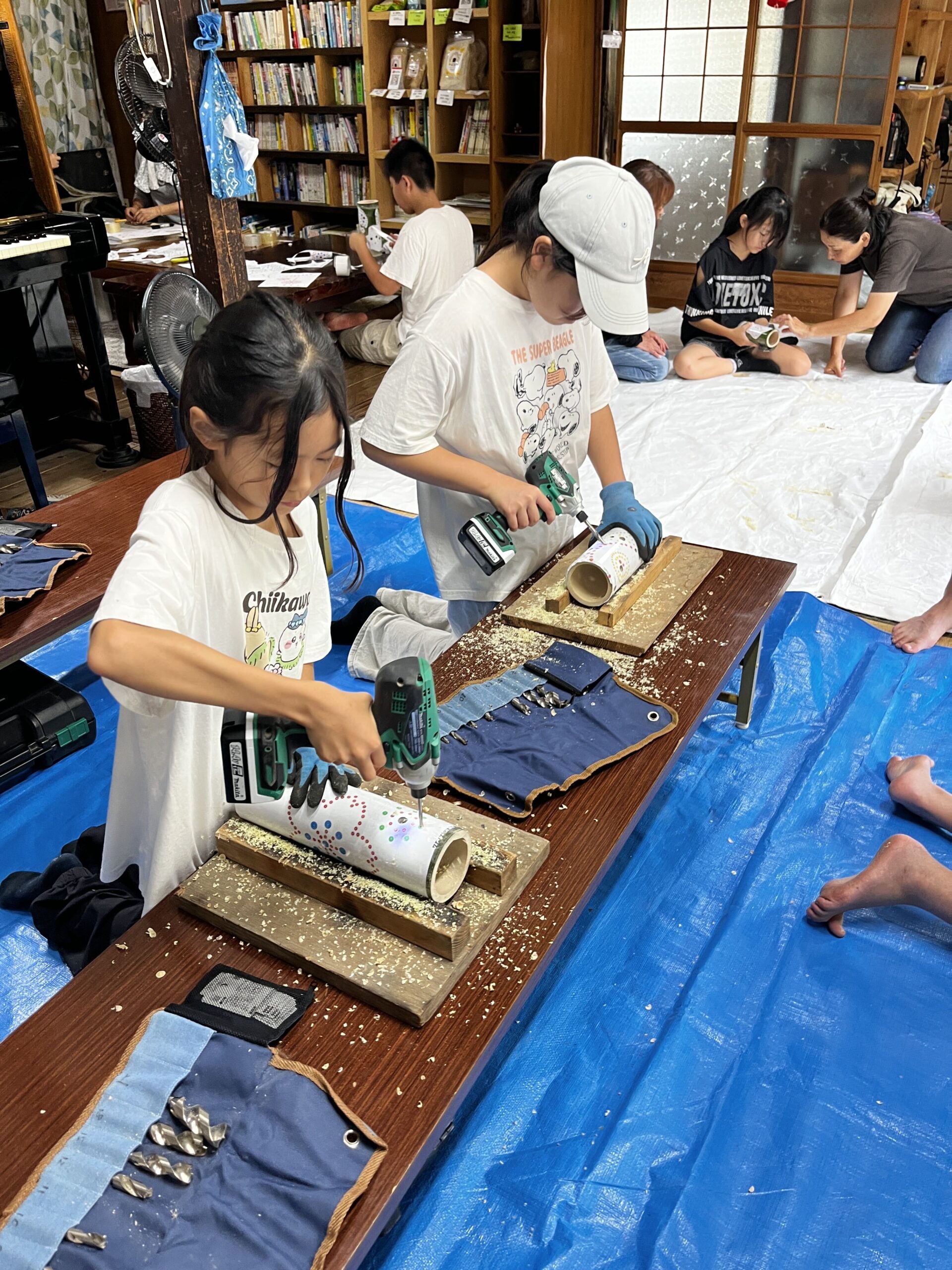 ドリルを使って竹に穴をあける作業に取り組む子どもたちの様子