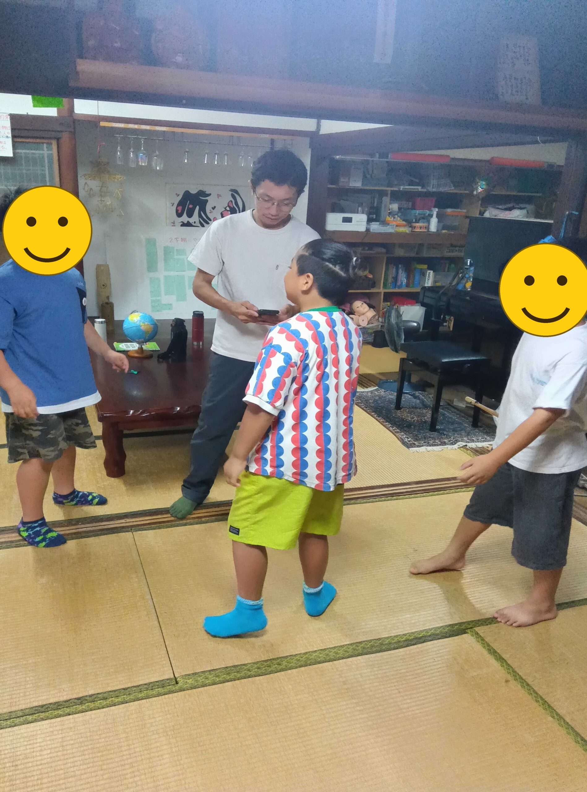 輪になって遊ぶ子どもたち(2人、顔にスタンプ加工)