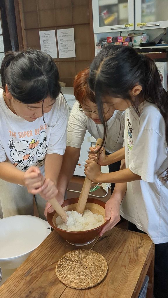 杵を使ってご飯をついておもちに仕上げる子どもたちとスタッフ