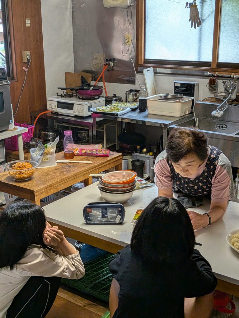台所で大人のお話を聞きながら、お菓子づくりをする子どもたち