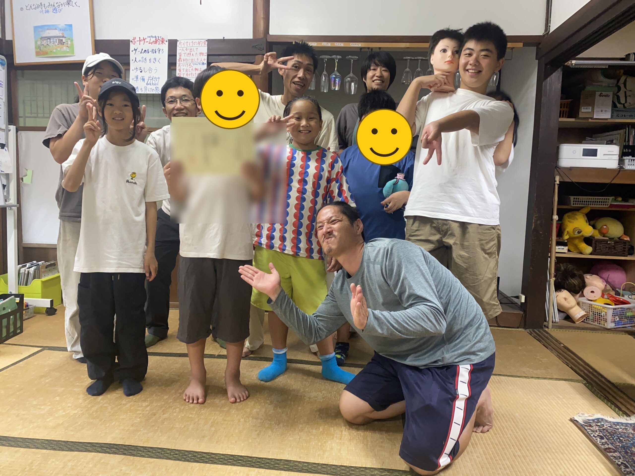 入学証書を手に、みんなで新しい仲間の入学をお祝いする様子(証書の氏名部分をぼかし、2人の顔にスタンプ加工)