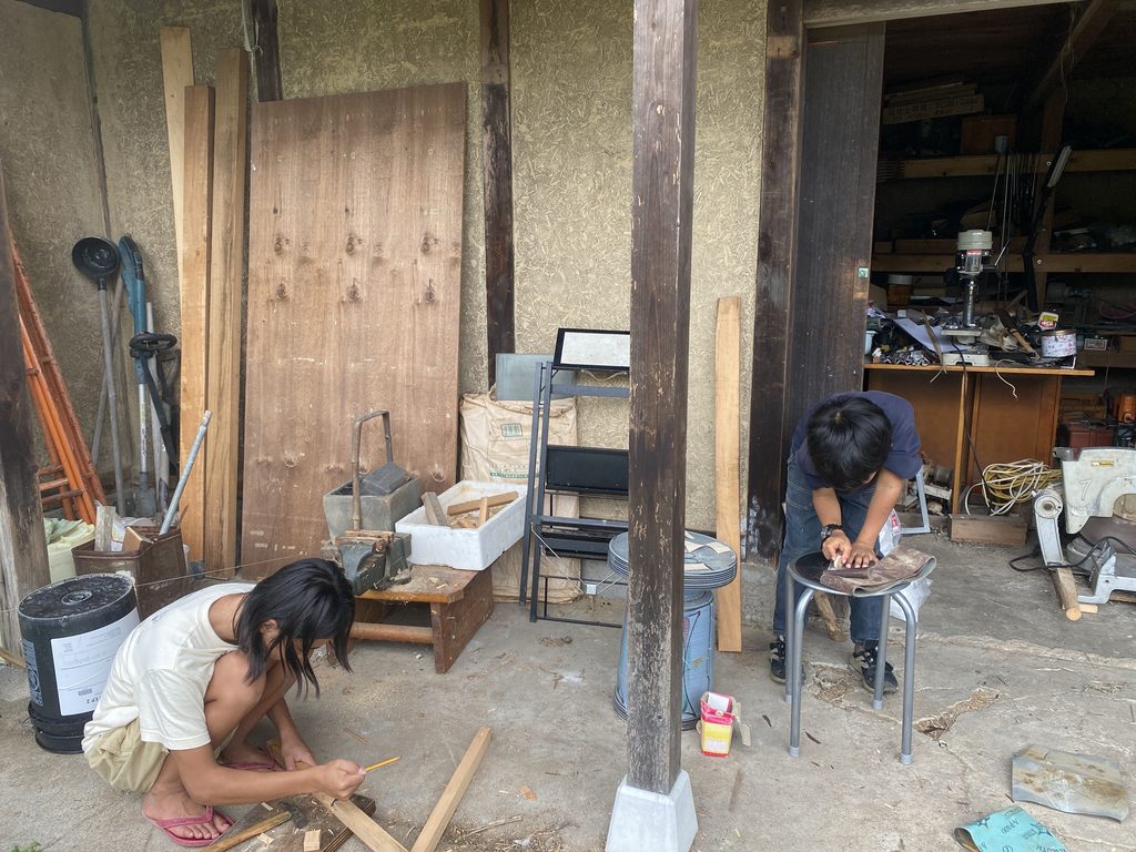工具小屋で木材を加工するスタッフと子ども