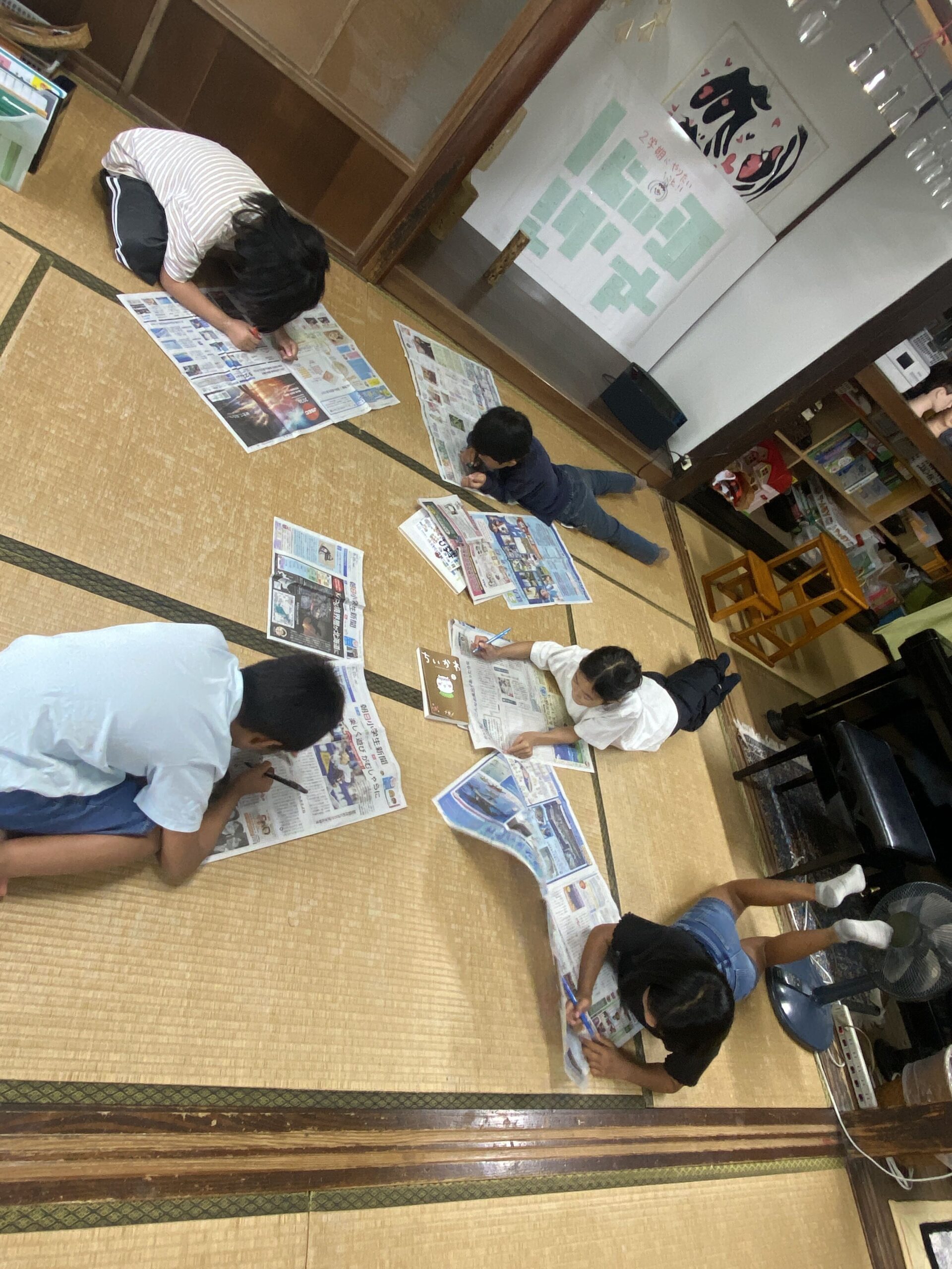 新聞紙の上でペンを持ち漢字を探す子どもの様子