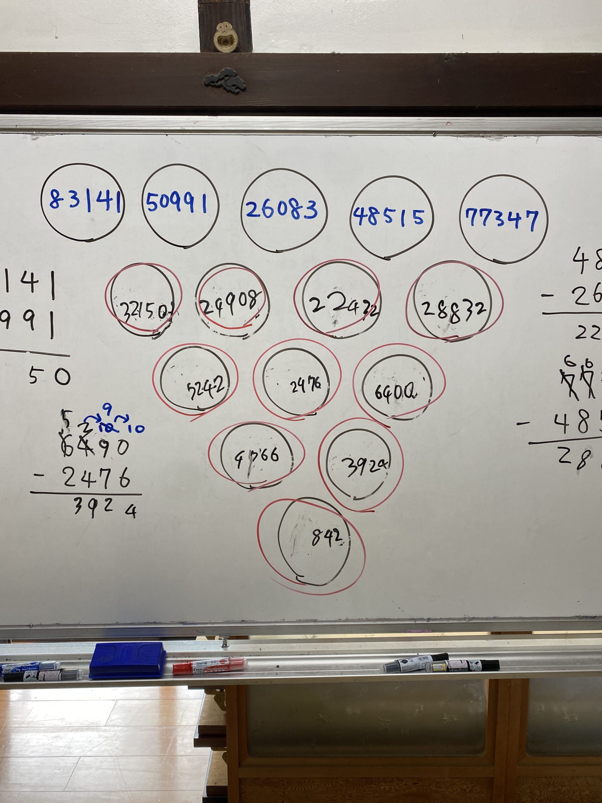 赤ペンで丸をつけたブドウ計算の答えが並ぶホワイトボード