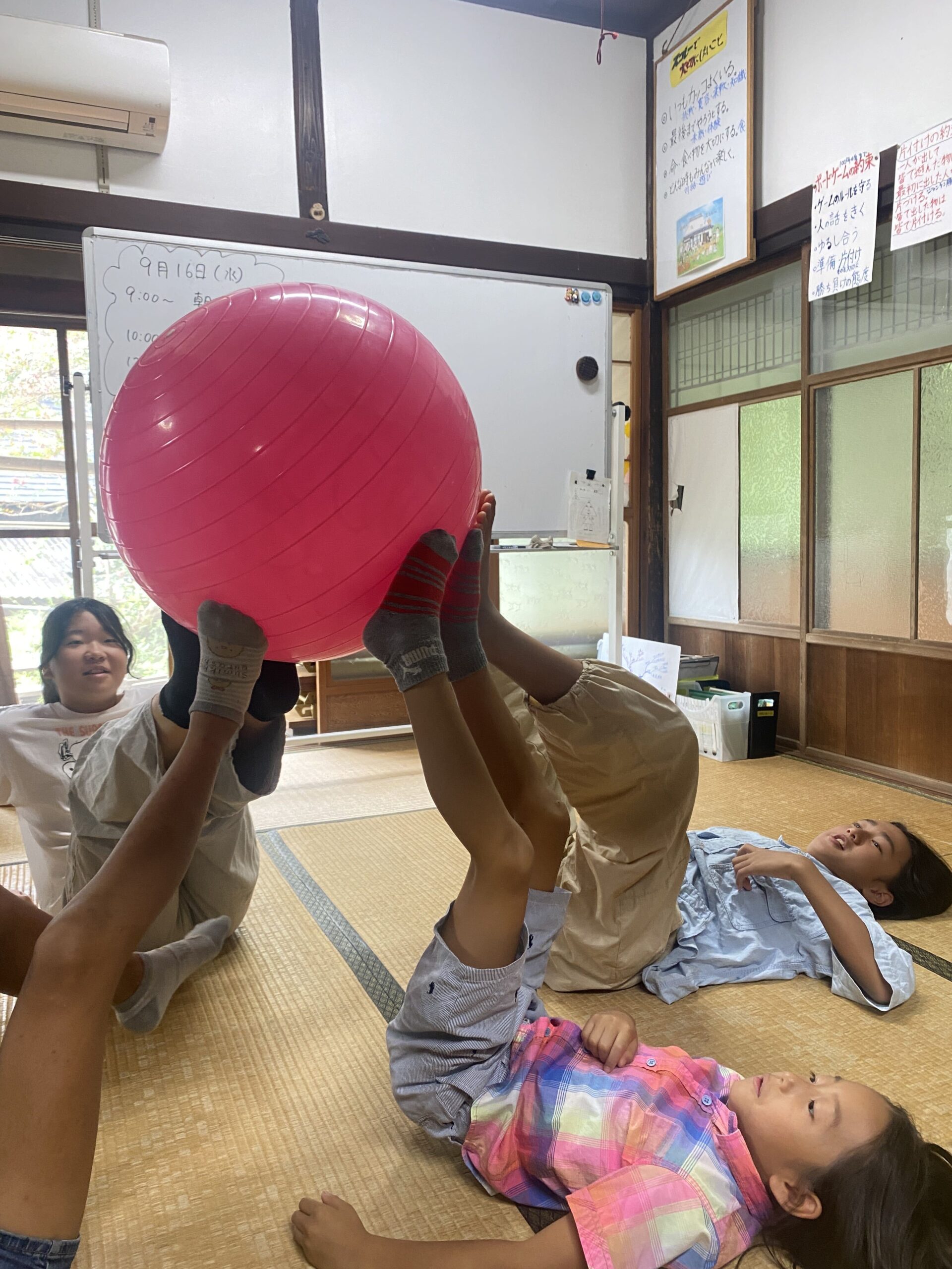 ボールを使ったレクで足を上げて支え合う子どもたちの様子
