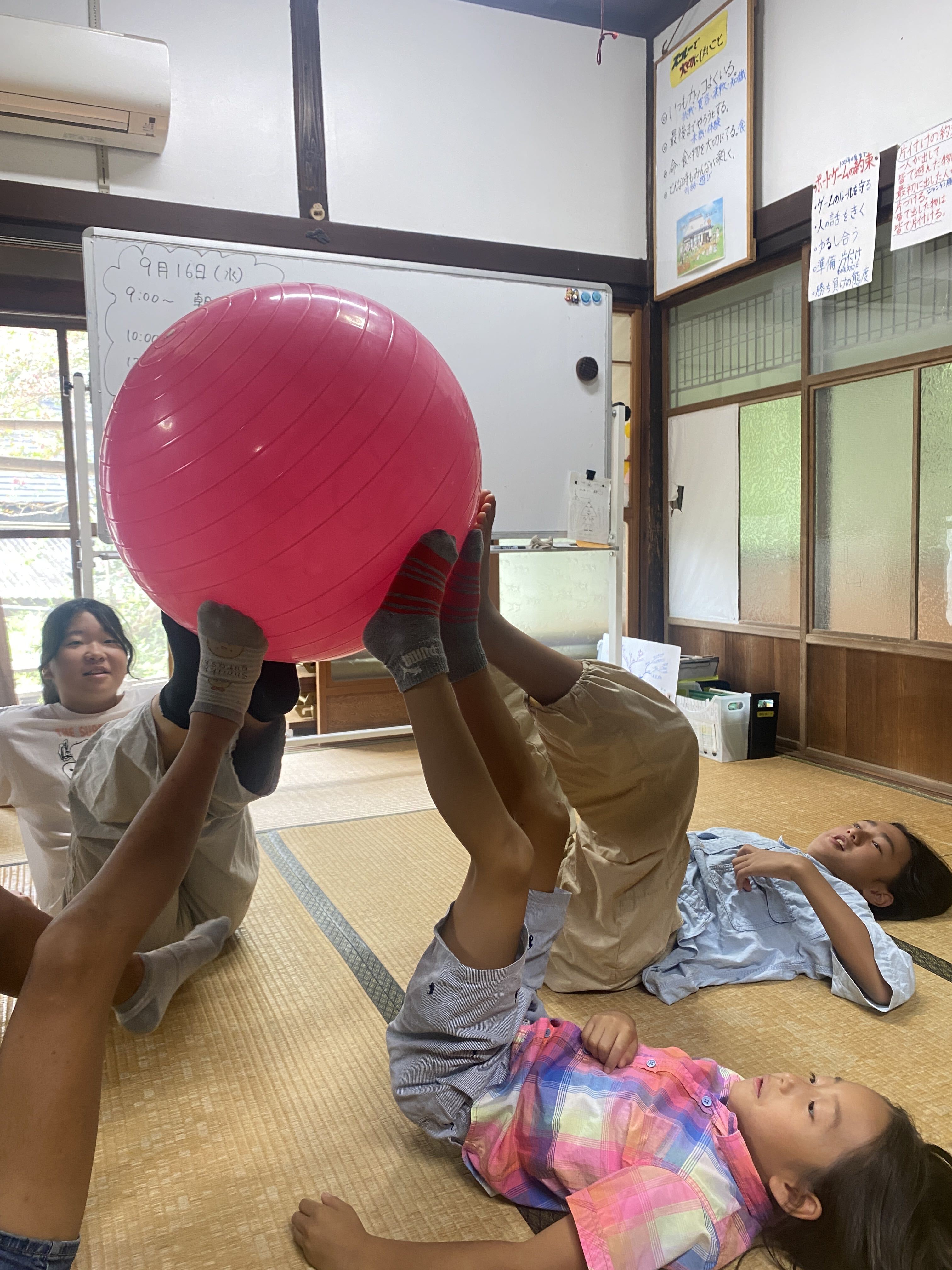 ボールを使ったレクで足を上げて支え合う子どもたちの様子