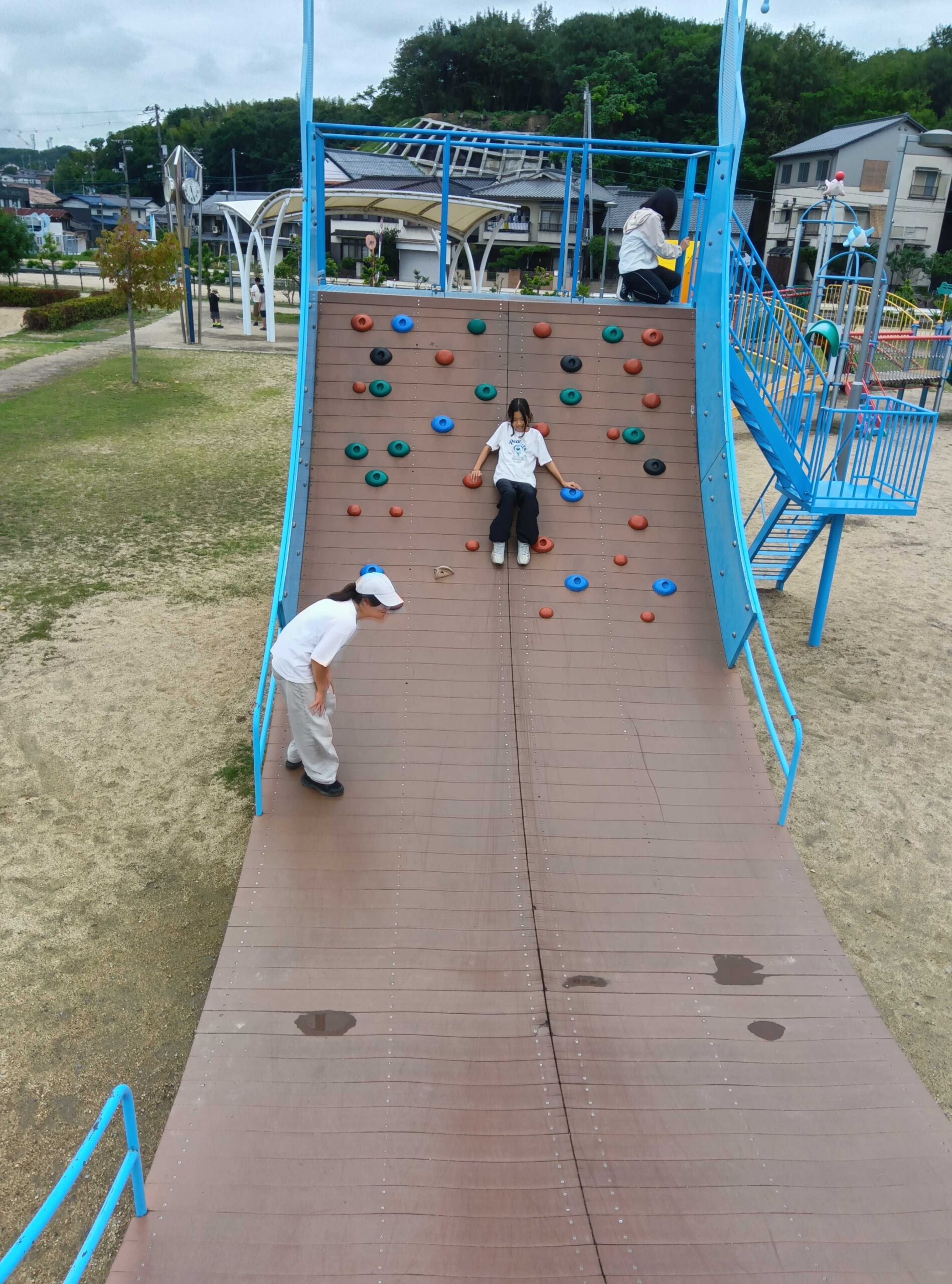 大きなボルダリング壁を登る子どもたち