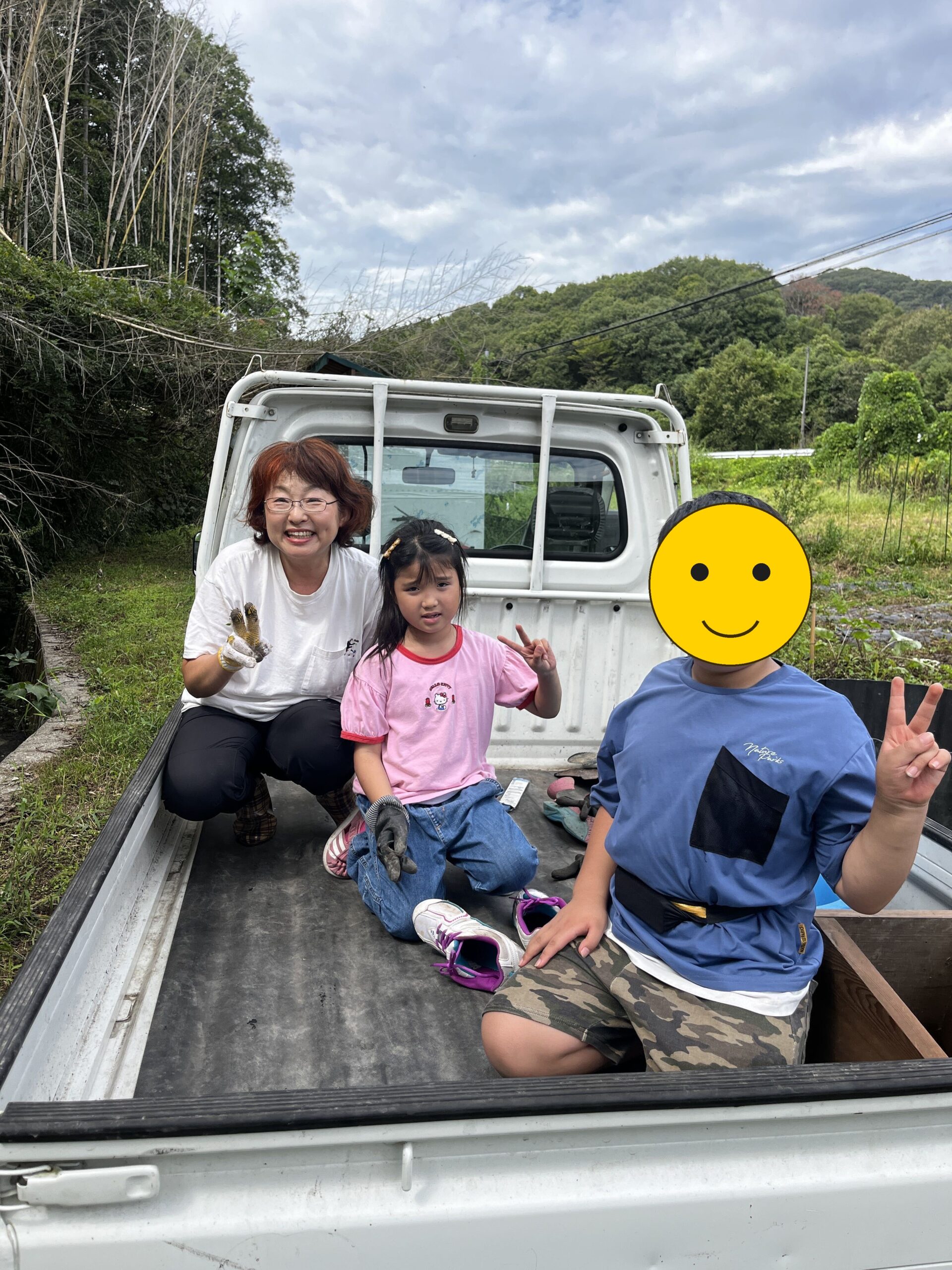 軽トラの荷台で捕まえた鶏を手にするスタッフと子どもたち(お子さんの顔を一部加工しています)