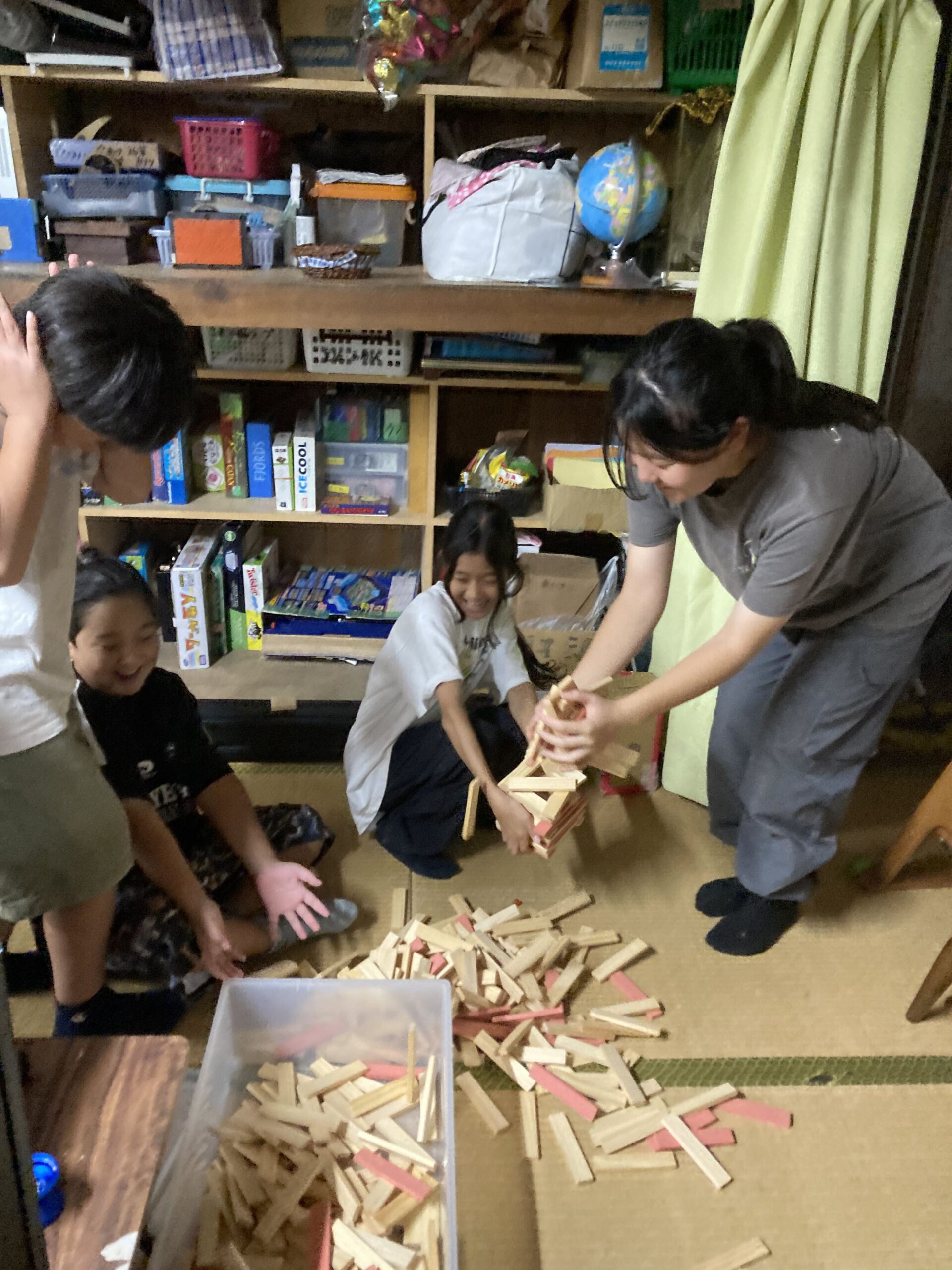 巨大なジェンガが崩れて笑い合う子どもたちの様子