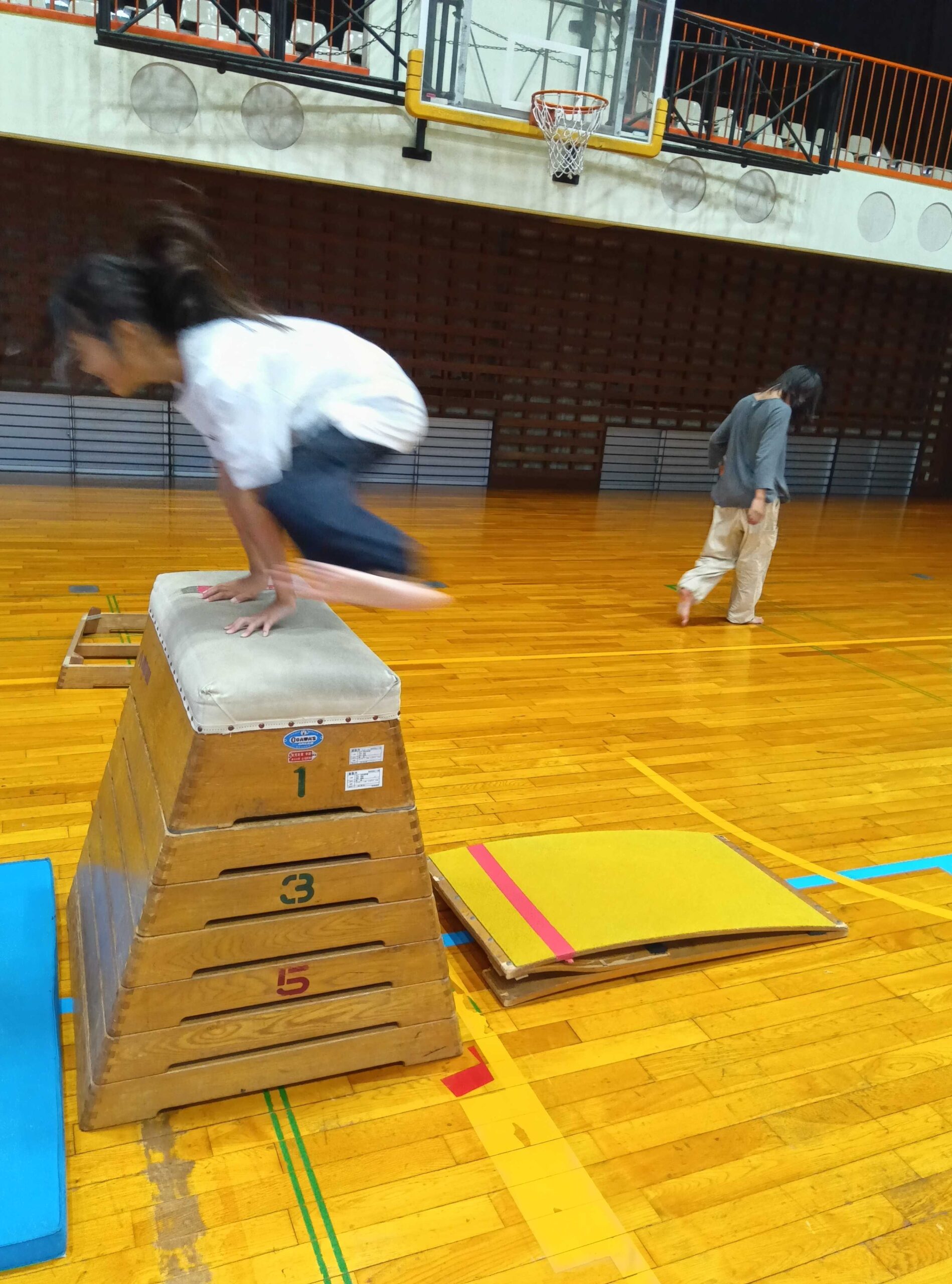 跳び箱に両手をついて跳び越える子ども