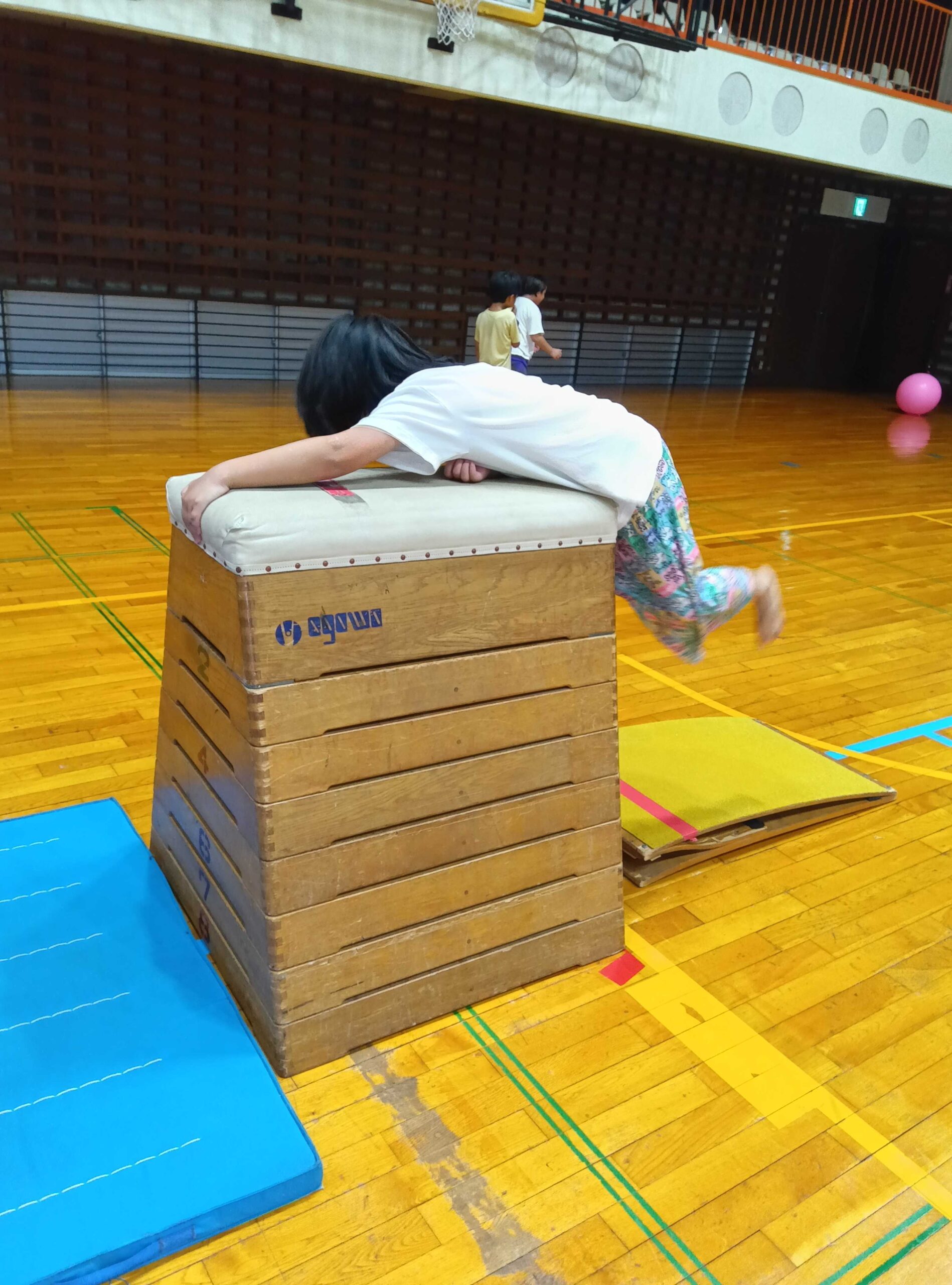 跳び箱の上におなかを乗せて体を支える子ども