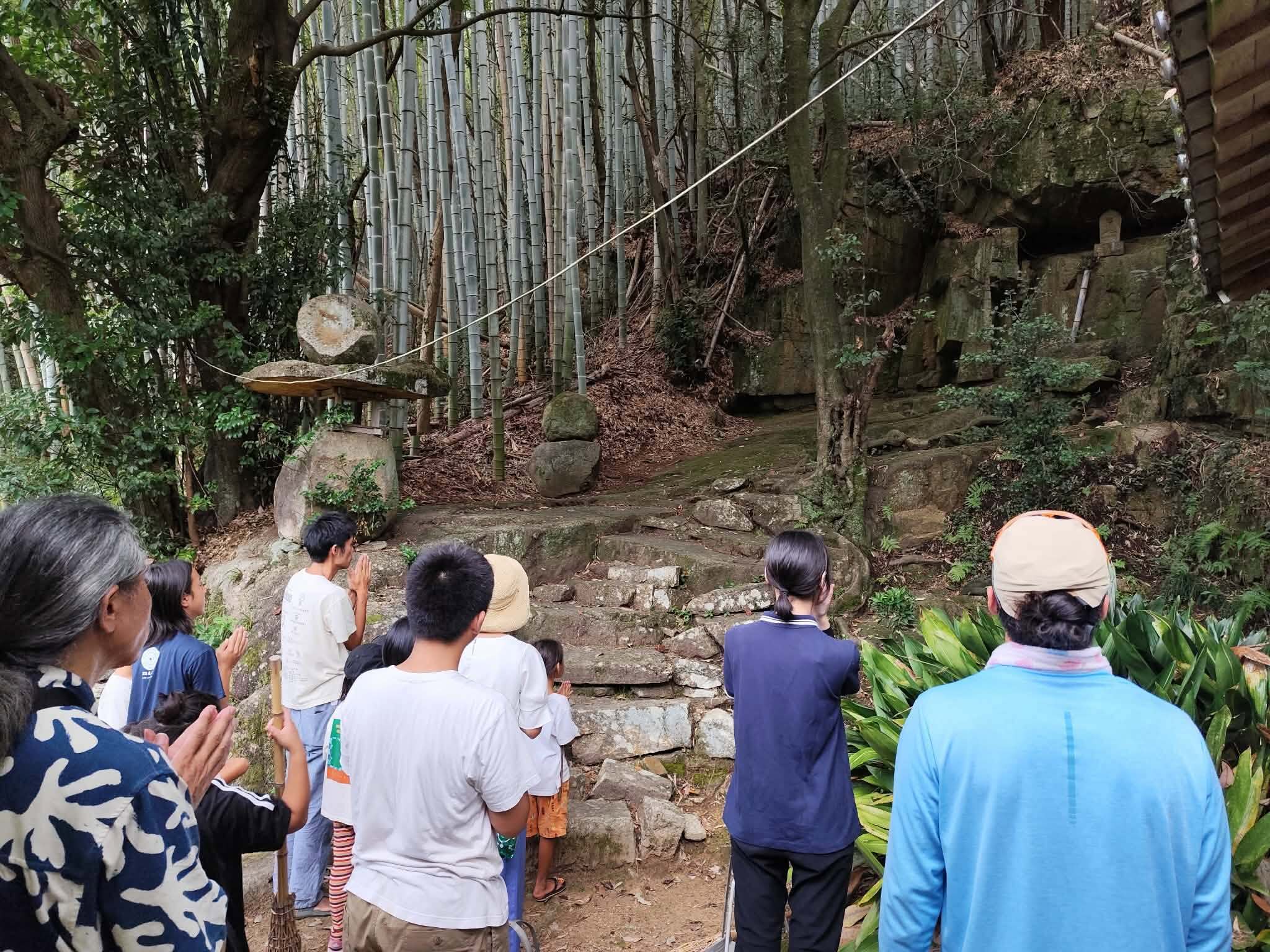 須田さんを大岩に案内し、みんなで手を合わせる様子
