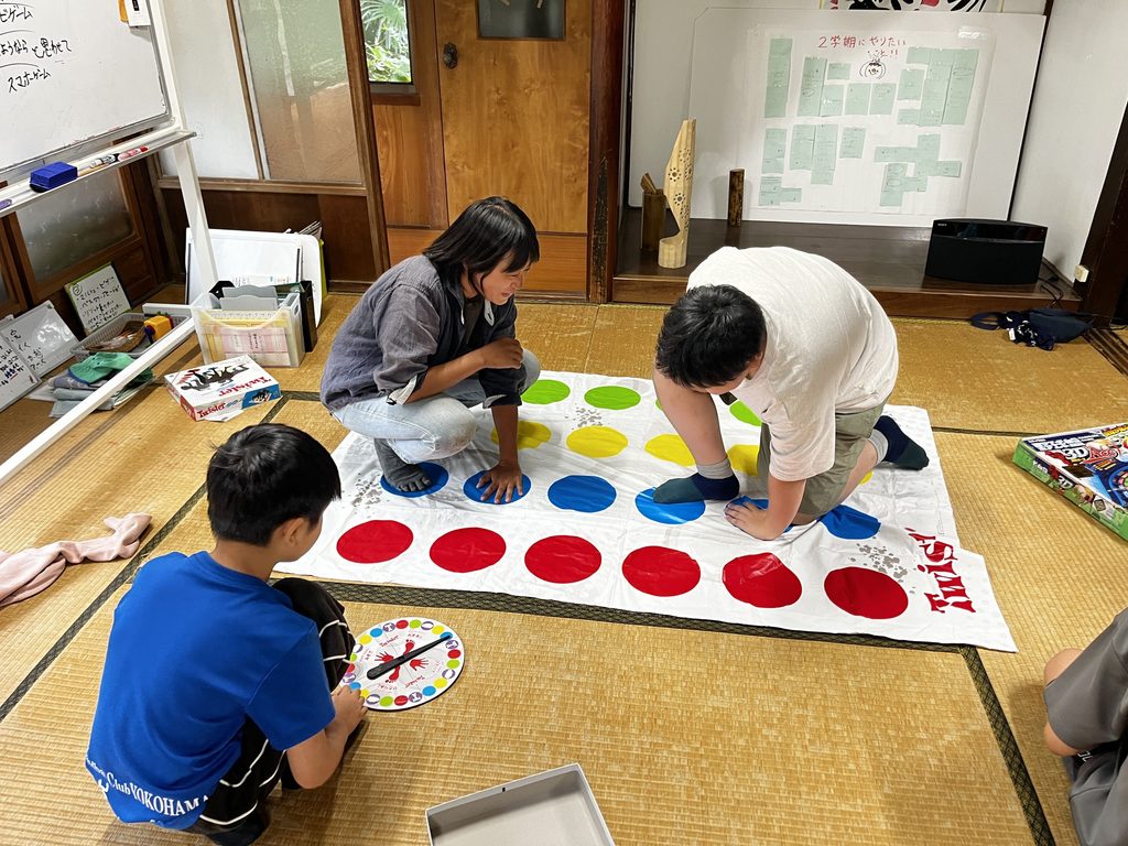 ツイスターゲームで、手足をのばしてマットに向かう子どもたち