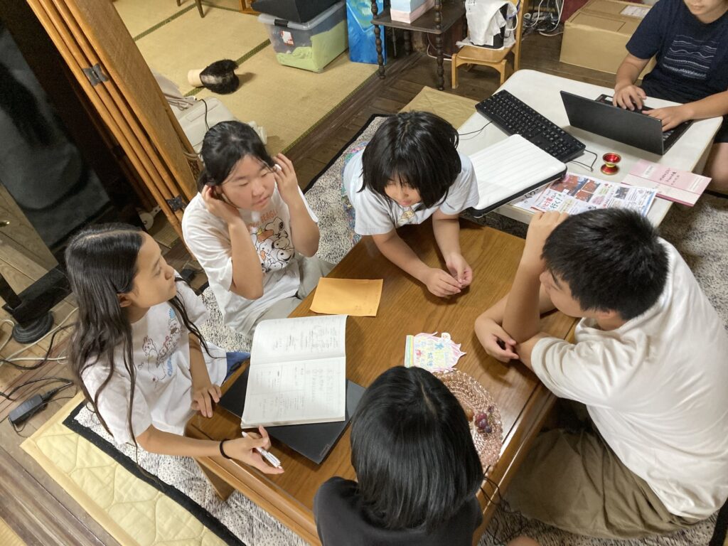 机を囲んで修学旅行の役割分担を話し合う子どもたち