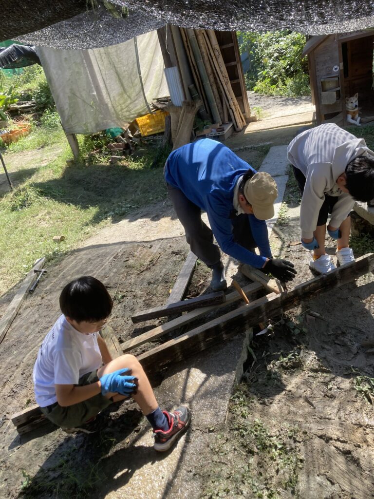 外した板を運び、作業を手伝う子ども