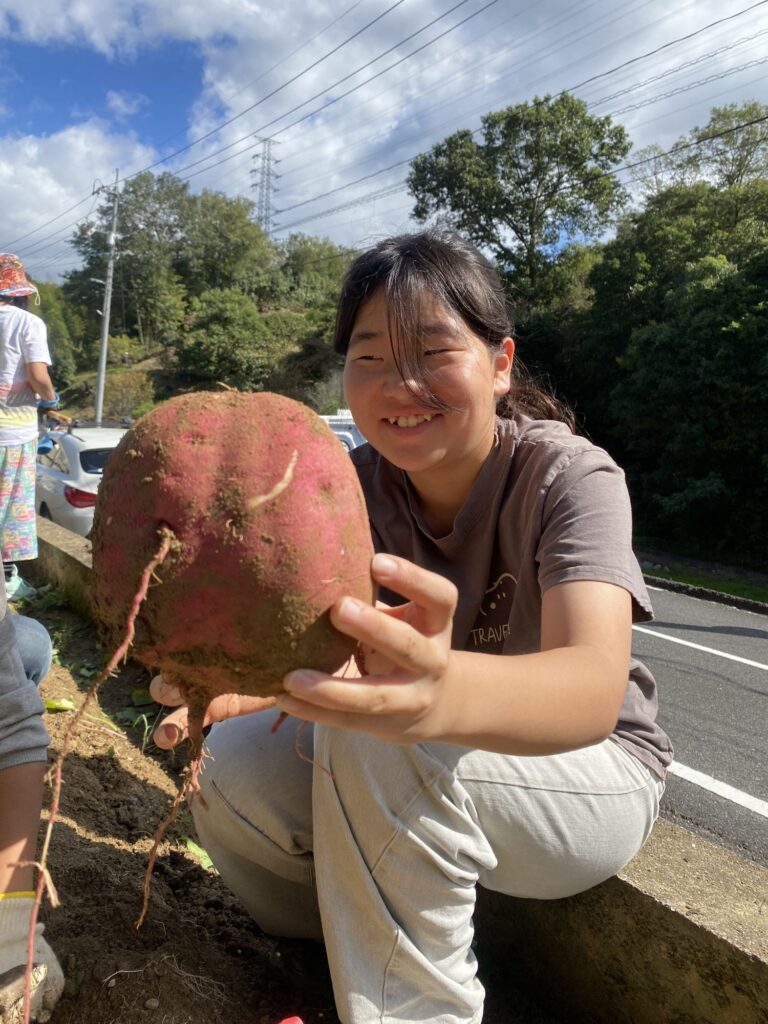 大きなサツマイモを手に、笑顔を見せる子ども