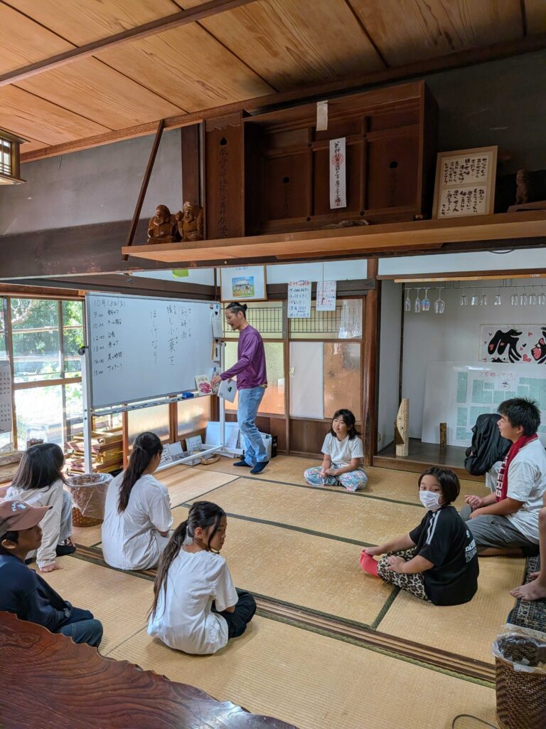 芭蕉の句が書かれたホワイトボードの前で、朝のワに集まる子どもたち
