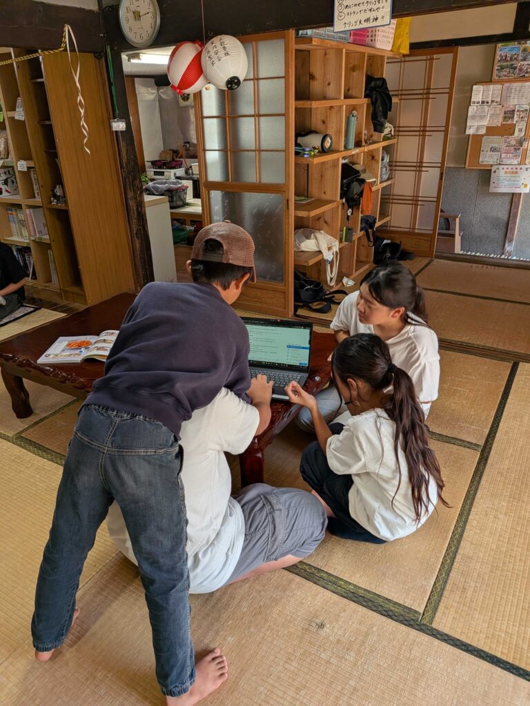 ちゃぶ台のパソコンをのぞきこんで、買い出しの内容をまとめる子どもたち