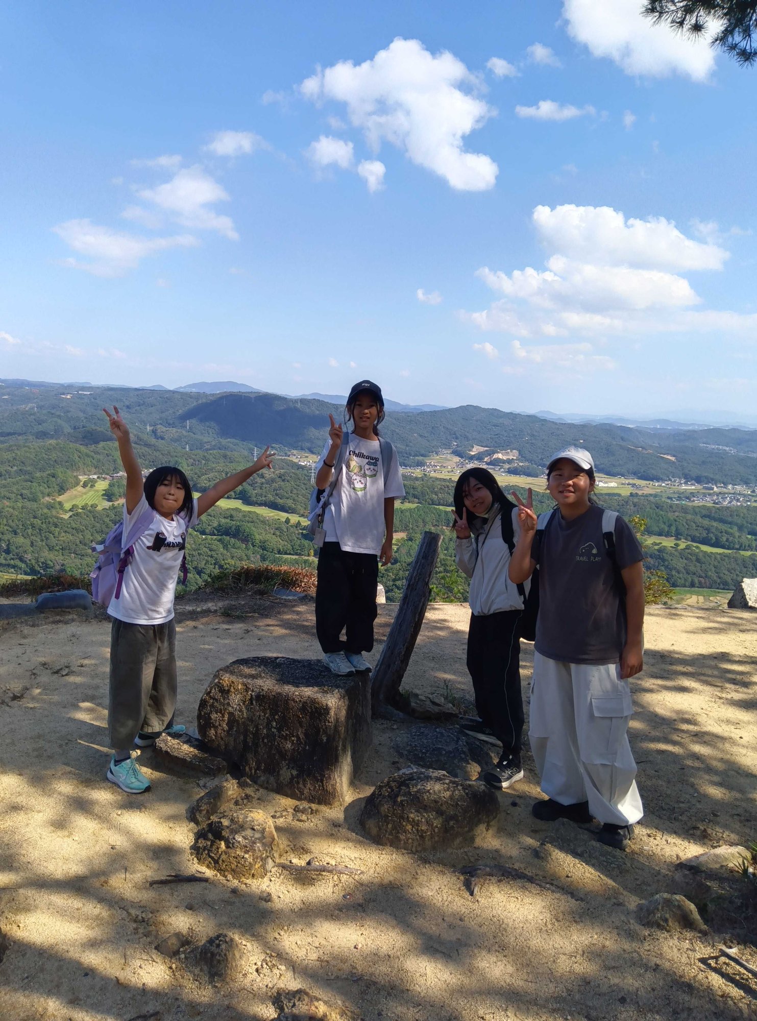 山並みを背に、両手を広げてポーズをとる子どもたち