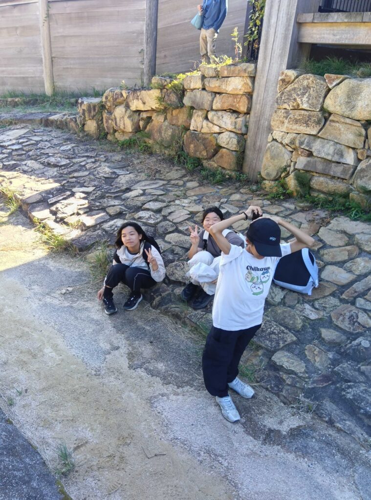 石垣の前の石畳で、ポーズを決める子どもたち