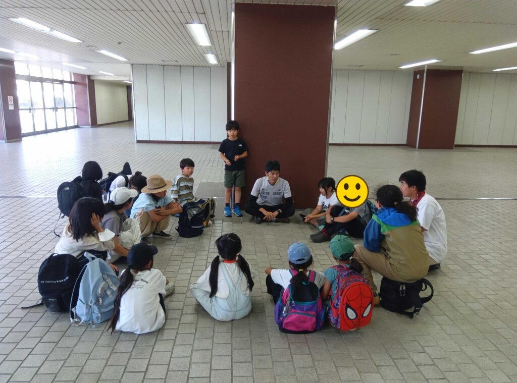 建物の中で輪になって座る子どもたちとスタッフ