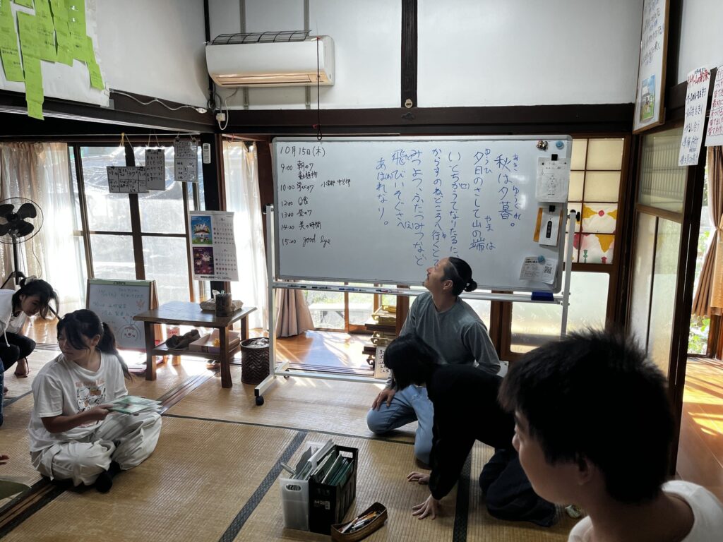 ホワイトボードに書かれた枕草子「秋は夕暮れ」を読む朝のスラ読み