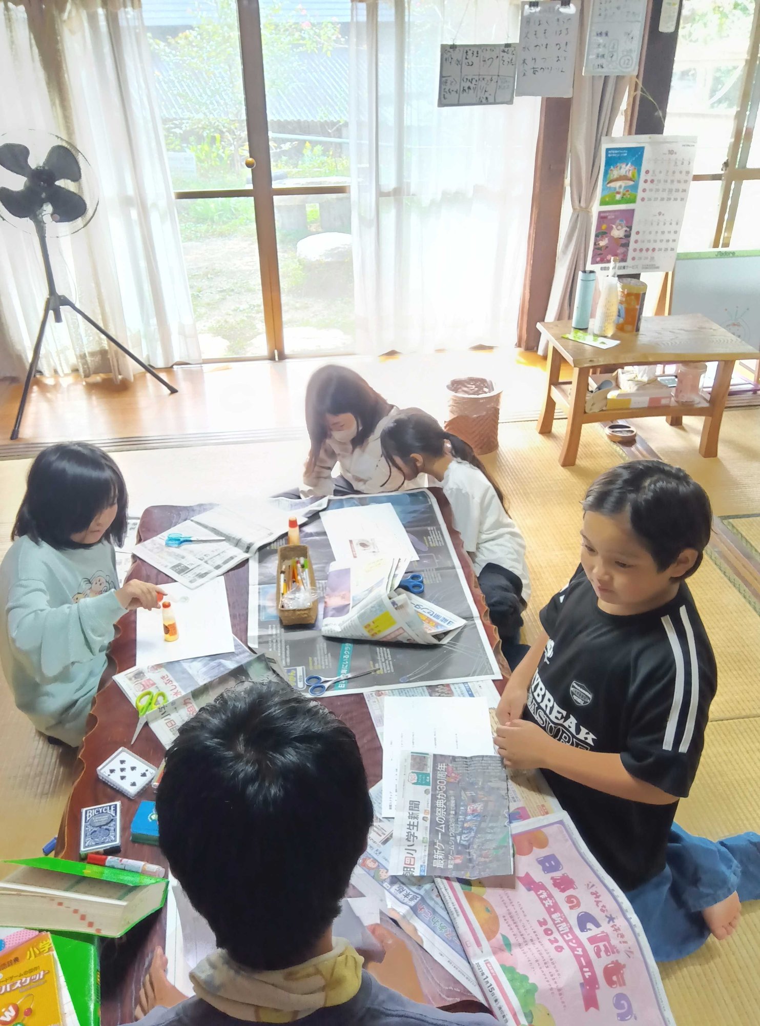 新聞を広げた座卓を囲んで、記事を切り貼りする子どもたち