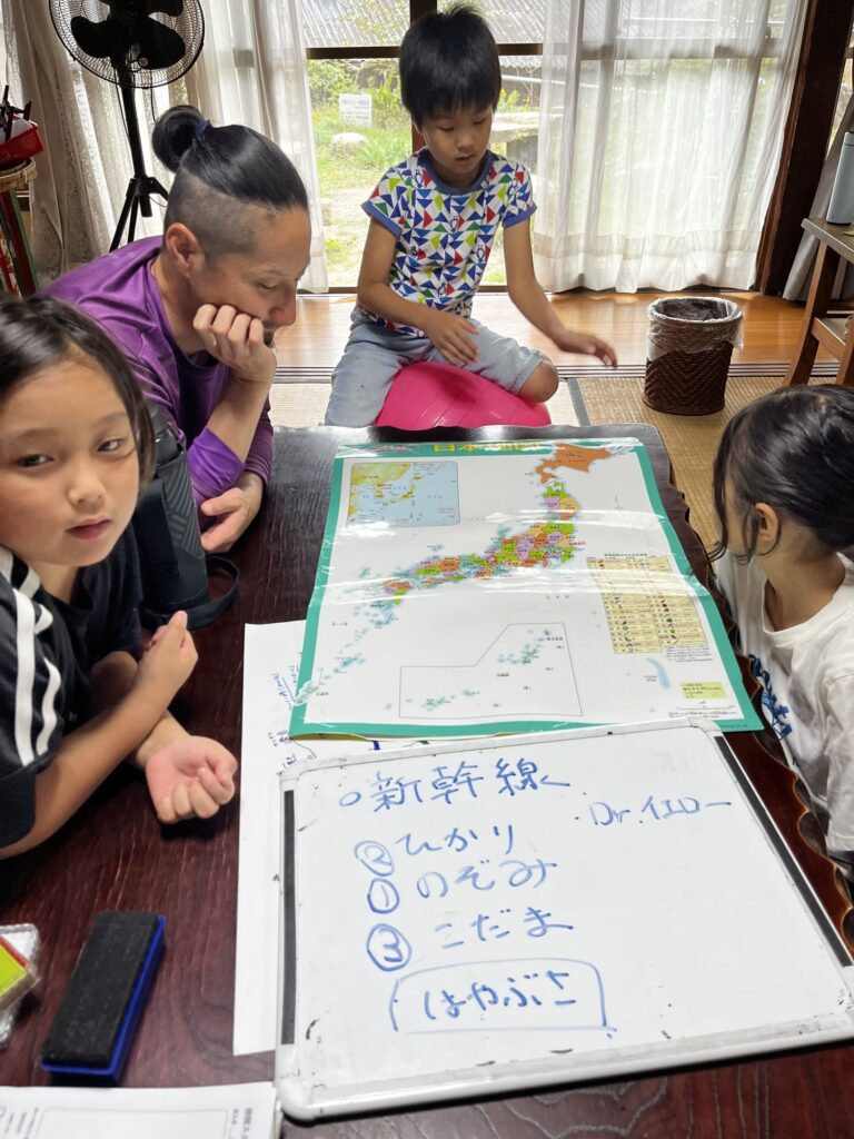 日本地図を広げて、新幹線の止まる県を見ていく子どもたちとスタッフ