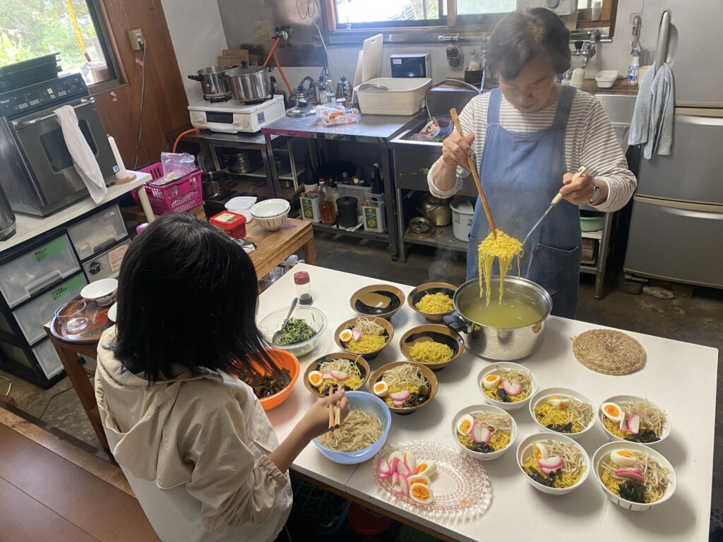 台所で、給食のラーメンを一杯ずつ盛りつける様子