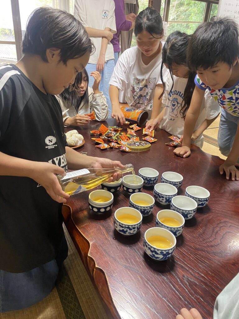 湯のみをずらりと並べて、みんなの分を注ぐ子どもたち