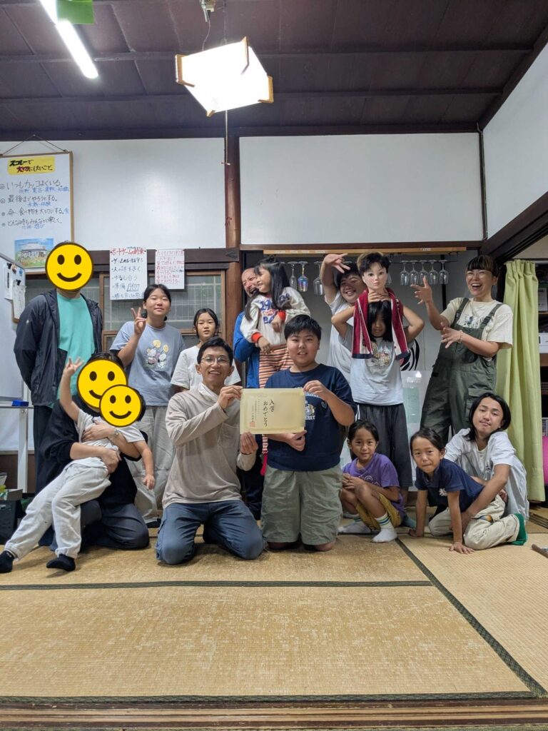入学証書を手に、子どもたちやスタッフと並んだ入学式の記念写真
