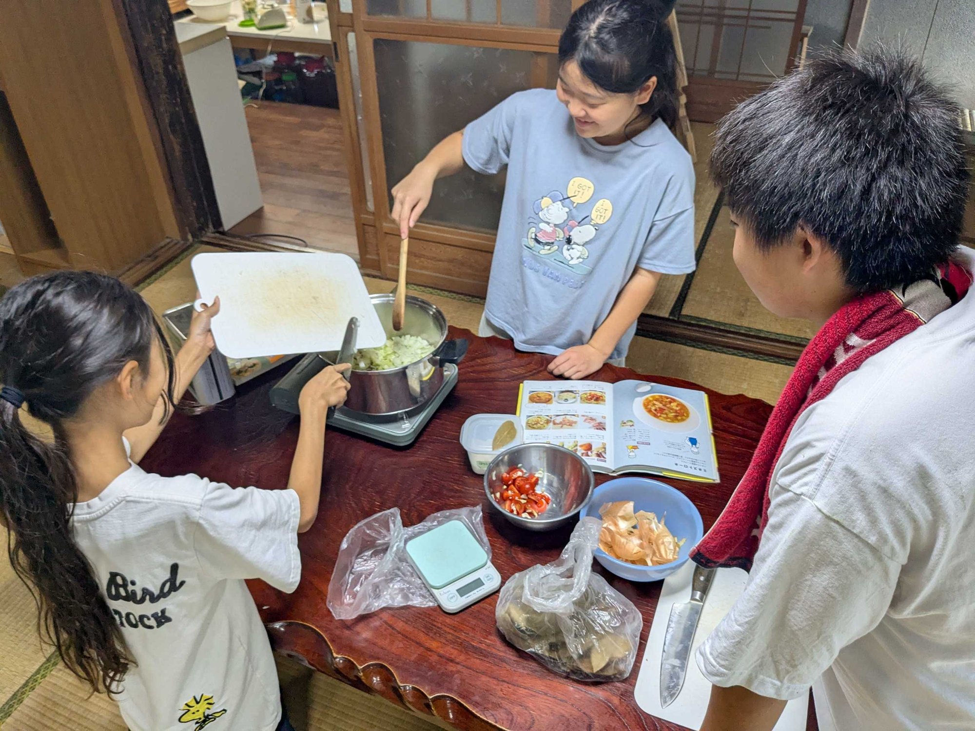 料理の本を見ながら、鍋でミネストローネを作る子どもたち