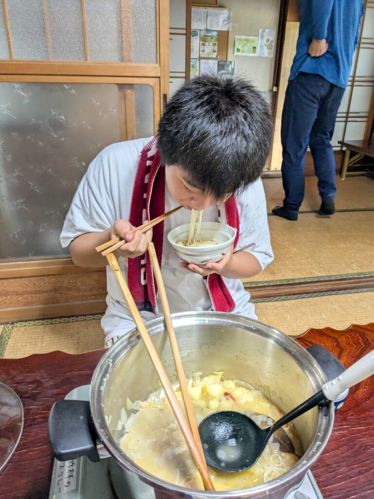 米麺を入れたミネストローネをすする子ども