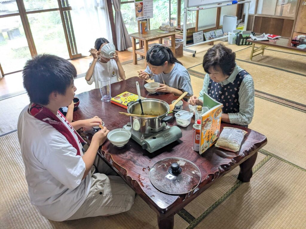 座卓の鍋を囲んで、できたミネストローネを食べる子どもたち