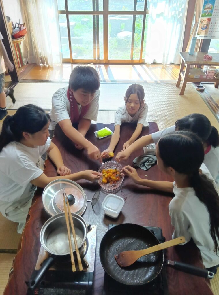 座卓を囲んで、できたニョッキをつまむ子どもたち