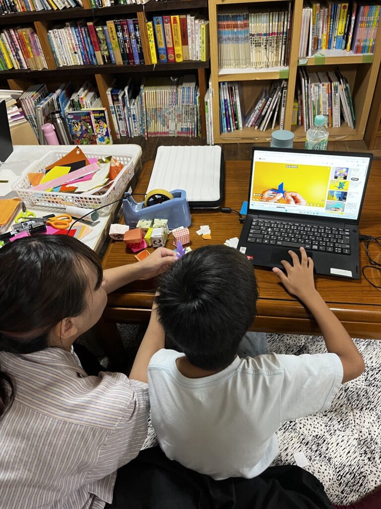 パソコンで折り方の動画を見ながら、折り紙に取り組む子ども