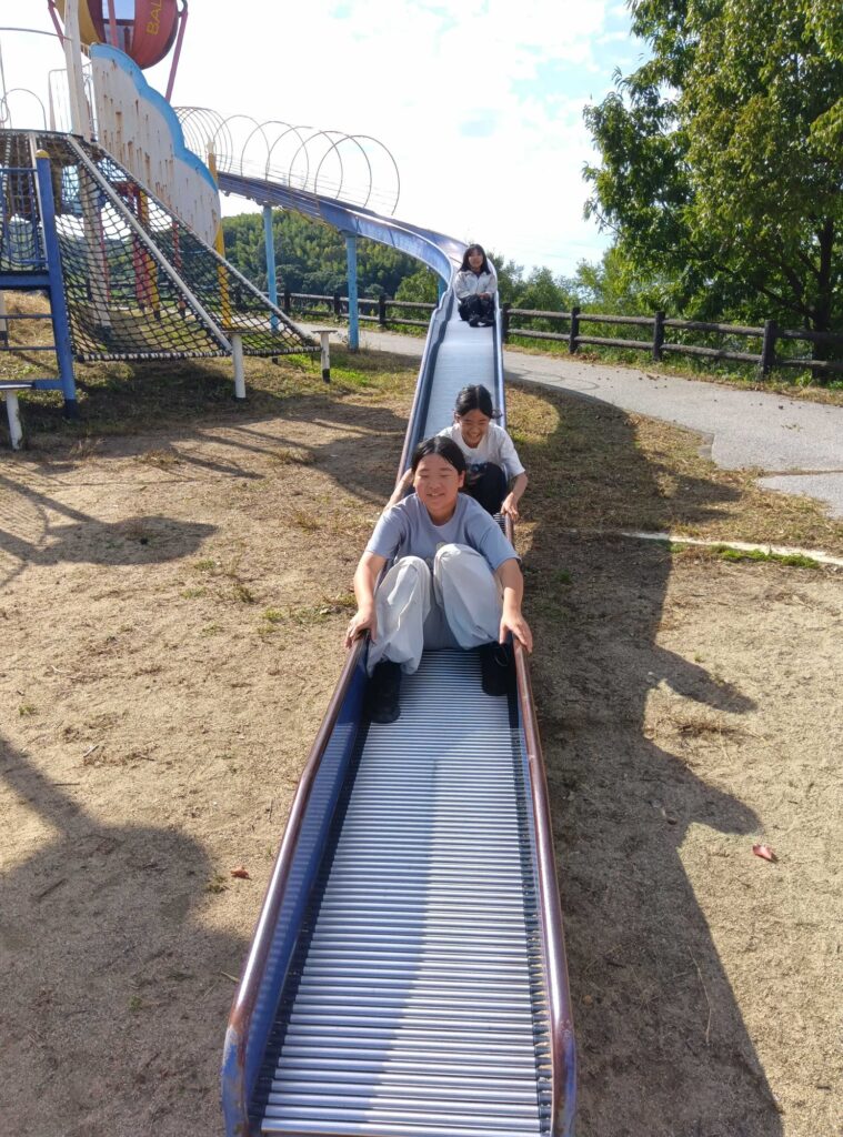 ローラー滑り台を連なって滑る子どもたち