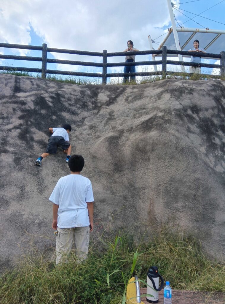大きな岩の斜面をよじ登る子どもたち