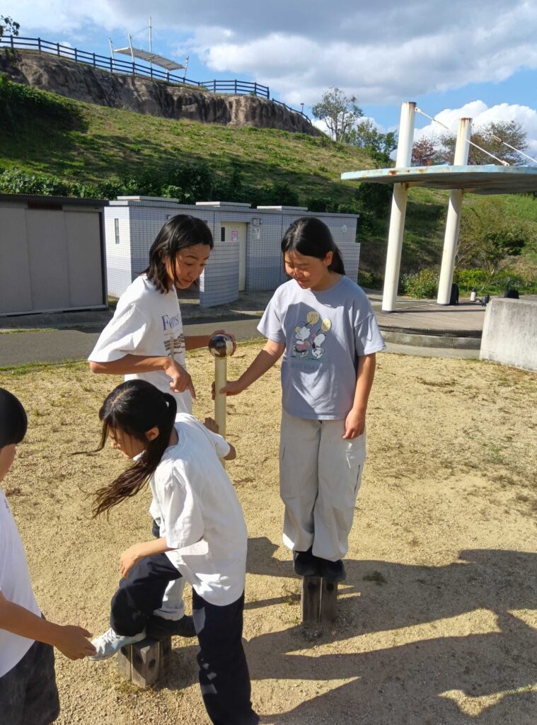 杭の上を渡り歩く遊具で遊ぶ子どもたち