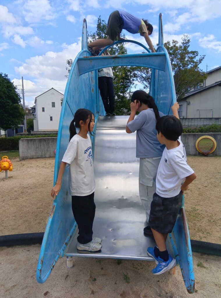 青い滑り台のまわりに集まる子どもたち