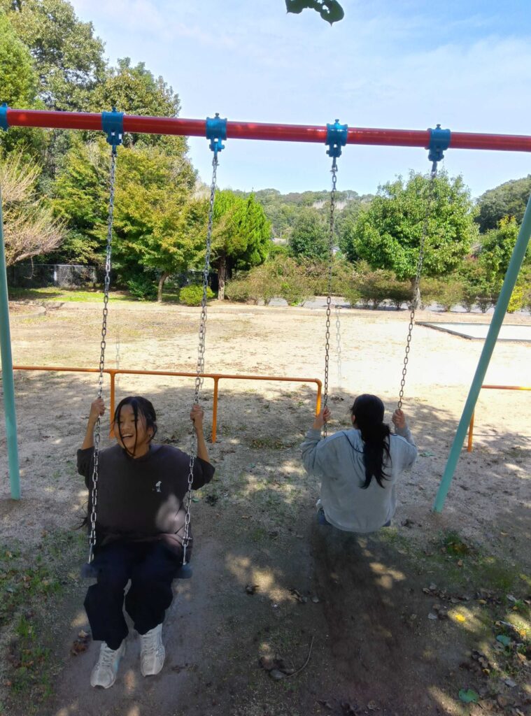 青空の下、ブランコをこぐ子どもたち