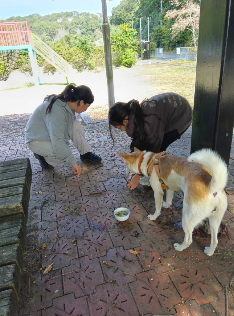 犬のサクラと、しゃがみこむ子どもたち