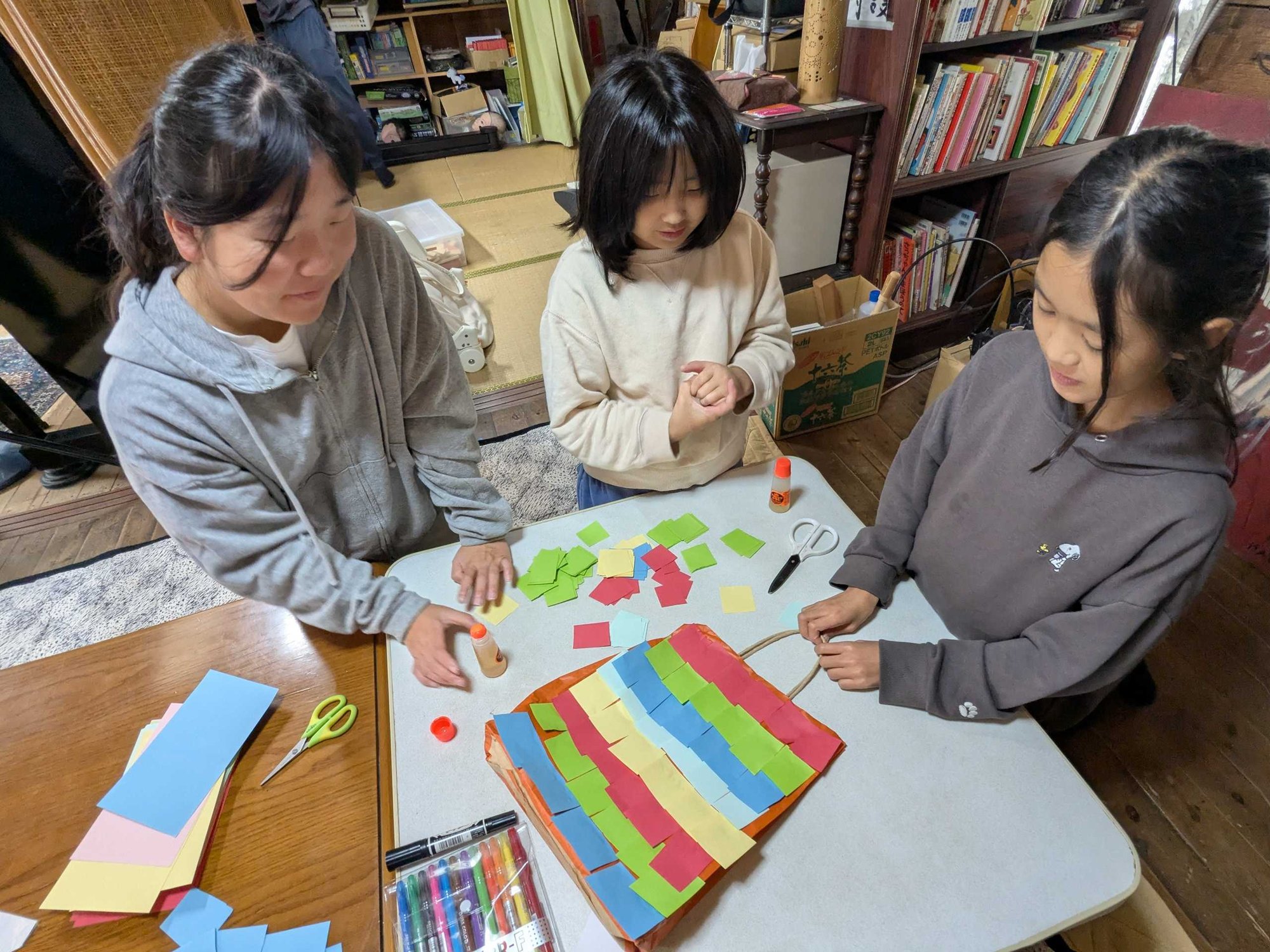 色紙を紙袋に貼って、ピニャータを作る子どもたち